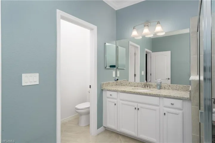 Bathroom featuring tile patterned flooring, crown molding, vanity, and toilet
