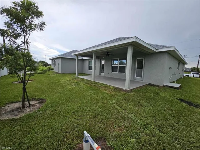 Back of property featuring a lawn, a patio area, and ceiling fan