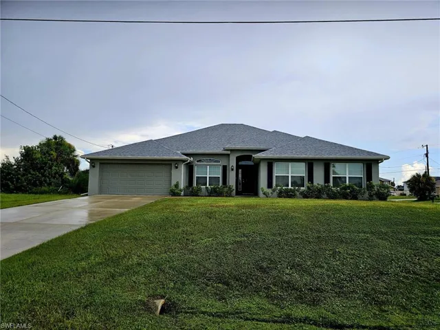 View of front facade featuring a front yard and a garage