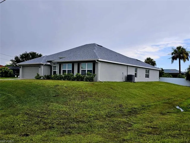 View of property exterior with a garage, cooling unit, and a lawn