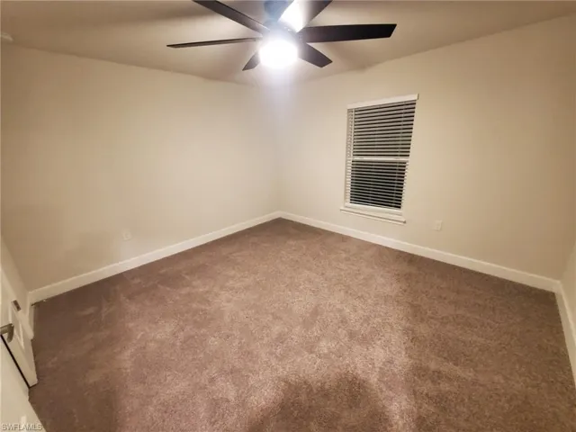 Carpeted empty room with ceiling fan