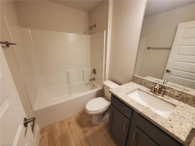 Full bathroom with vanity, toilet, wood-type flooring, and bathtub / shower combination