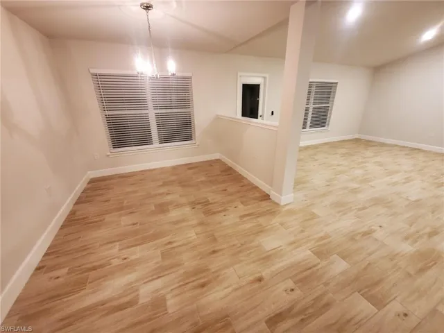 Unfurnished room with a chandelier and light wood-type flooring