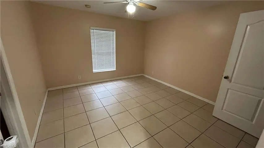 Empty room with ceiling fan and light tile patterned flooring