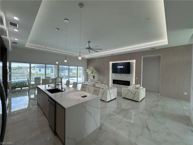 Kitchen with a raised ceiling, a ceiling fan, light marble finish floors, open floor plan, and recessed lighting