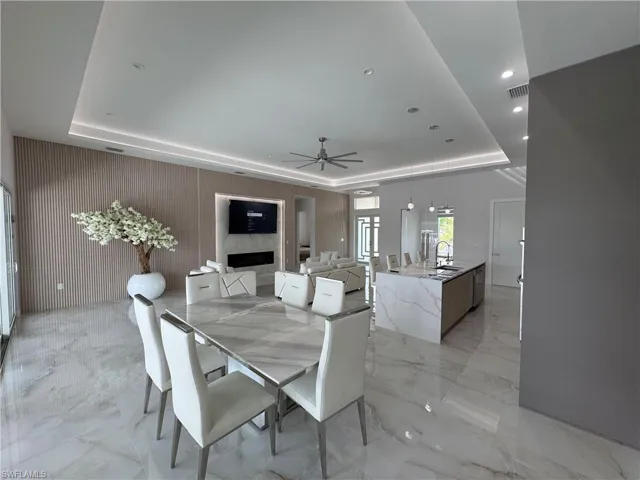 Dining area featuring a raised ceiling, light marble finish flooring, ceiling fan, and recessed lighting