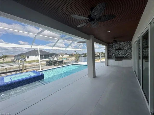 View of pool featuring a water view, area for grilling, an in ground hot tub, a grill, and a patio
