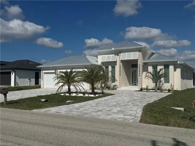 View of front of property with a garage and a front lawn