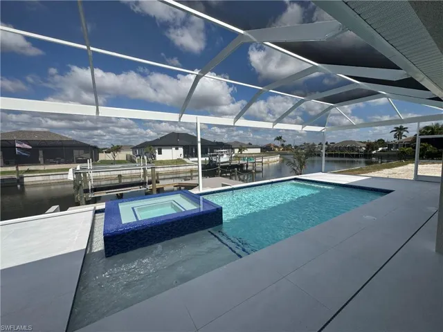 View of pool with a patio, an in ground hot tub, a lanai, a boat dock, and a water view