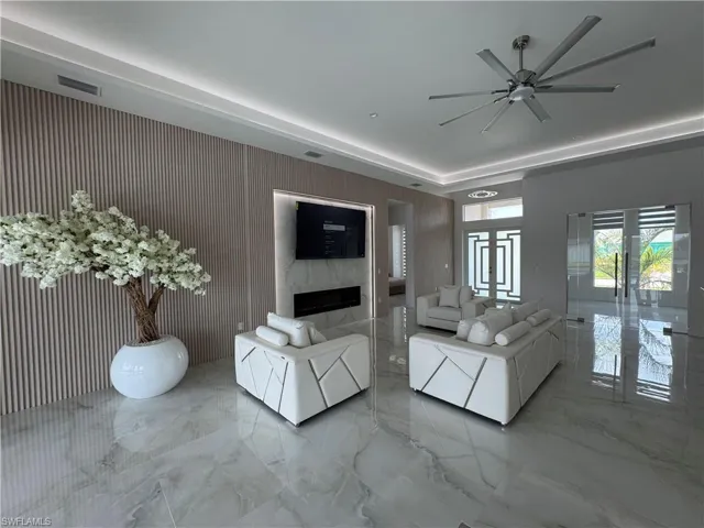 Living room featuring marble tiled flooring, a ceiling fan, and a fireplace