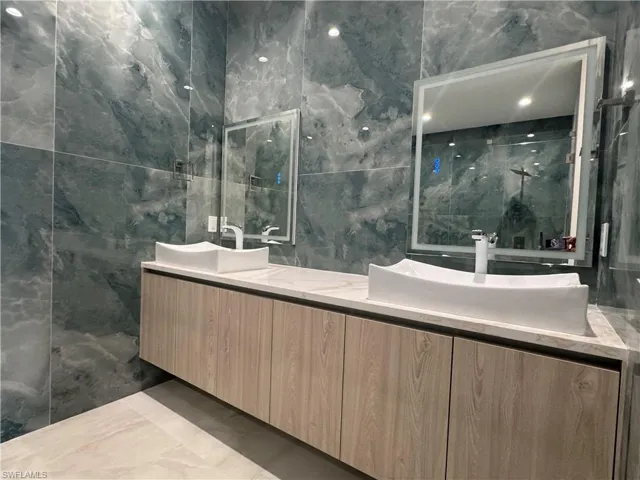 Bathroom featuring vanity, tile walls, and a shower