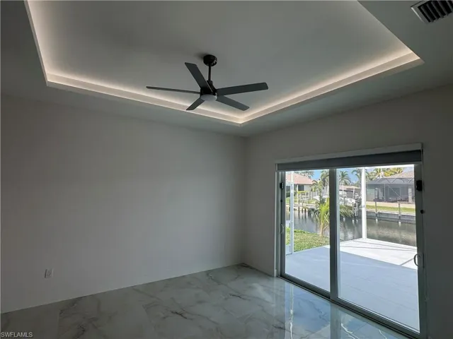 Empty room featuring a water view, ceiling fan, and a tray ceiling