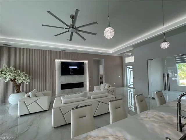 Living room with light marble finish flooring, a ceiling fan, and a fireplace