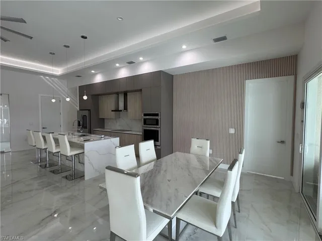 Dining space featuring light marble finish floors, recessed lighting, and an accent wall