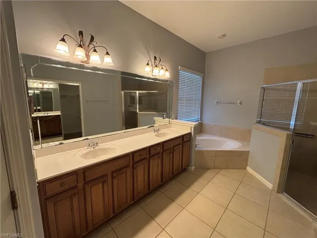 Bathroom with double vanity, a bath, a stall shower, and light tile patterned floors