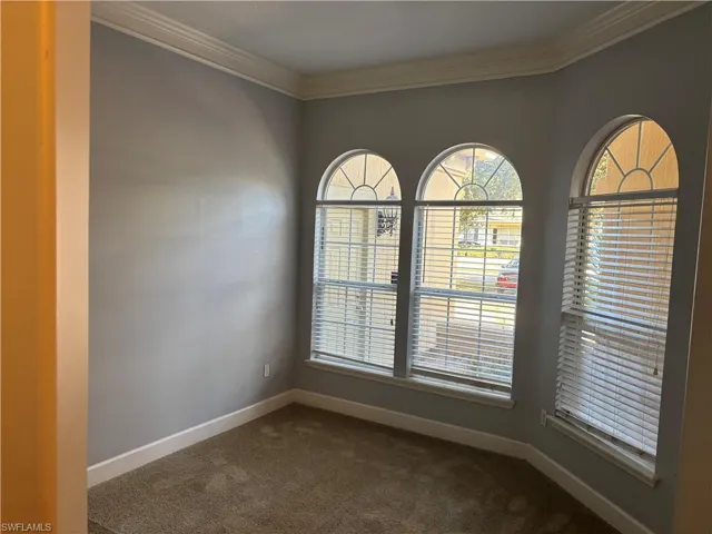 Empty room with ornamental molding and dark carpet