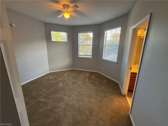 Unfurnished bedroom featuring a textured ceiling, carpet floors, a ceiling fan, and ensuite bath