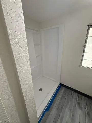 Full bath with a shower stall and wood finished floors