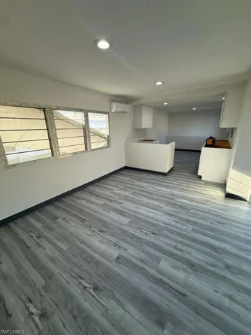 Unfurnished living room featuring recessed lighting, dark wood-style flooring, and a wall mounted AC