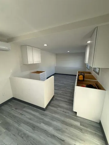 Kitchen with white cabinets, recessed lighting, an AC wall unit, and dark wood-style flooring