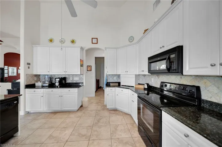 Kitchen with black appliances, a ceiling fan, arched walkways, and visible vents