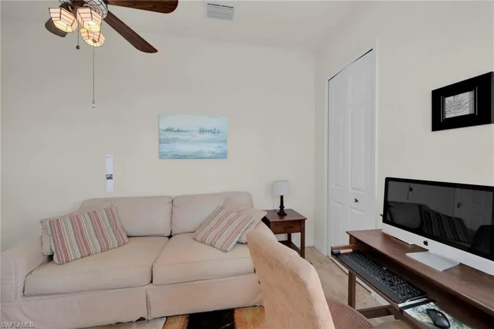 Carpeted living area with visible vents, baseboards, and ceiling fan