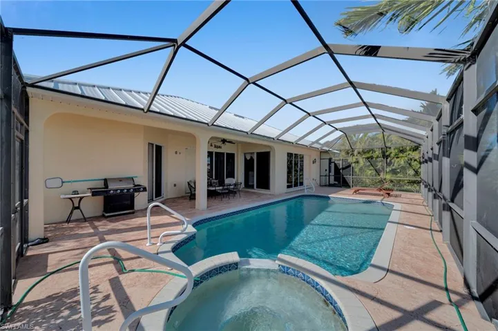 View of pool featuring a pool with connected hot tub, a lanai, a patio area, area for grilling, and a ceiling fan