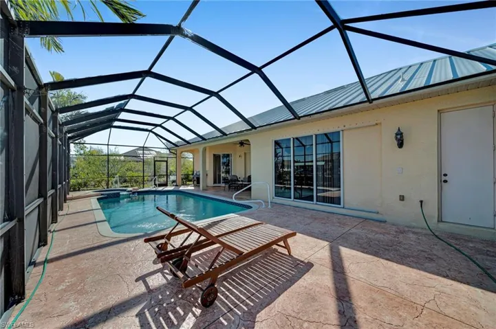 View of pool featuring glass enclosure, a patio, ceiling fan, and a pool with connected hot tub