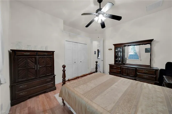 Bedroom with wood finished floors, visible vents, a closet, and ceiling fan