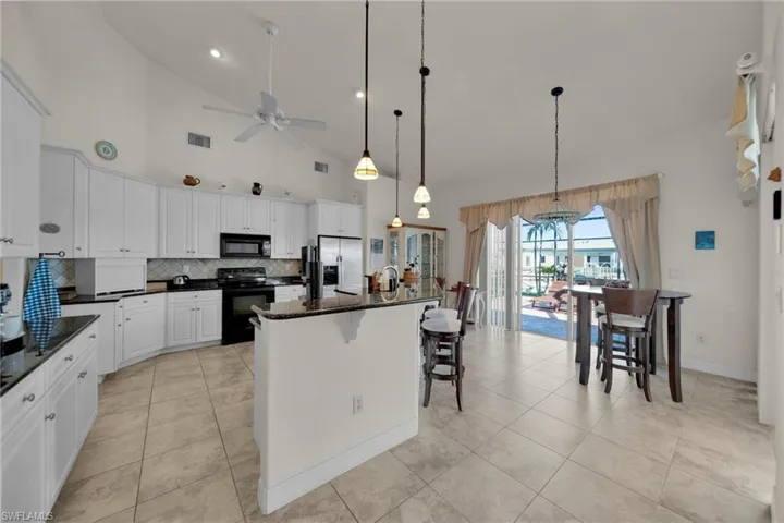 Kitchen with visible vents, ceiling fan, decorative backsplash, black appliances, and white cabinetry