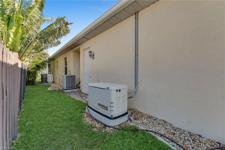 Exterior details with stucco siding, cooling unit, a power unit, and fence