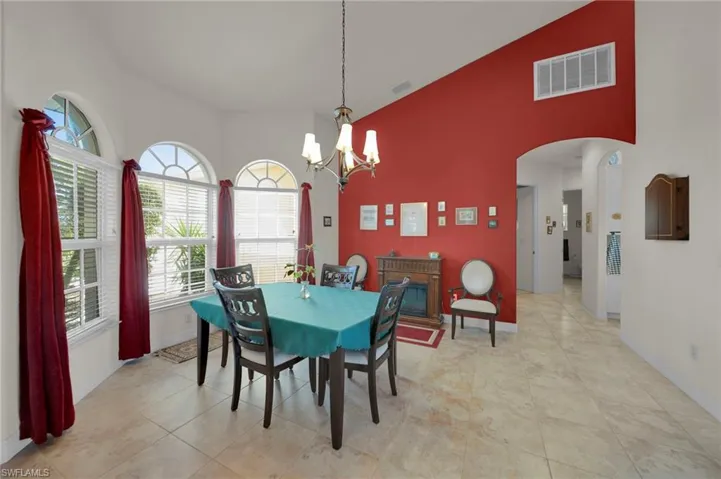 Dining space featuring visible vents, baseboards, an inviting chandelier, a high ceiling, and arched walkways