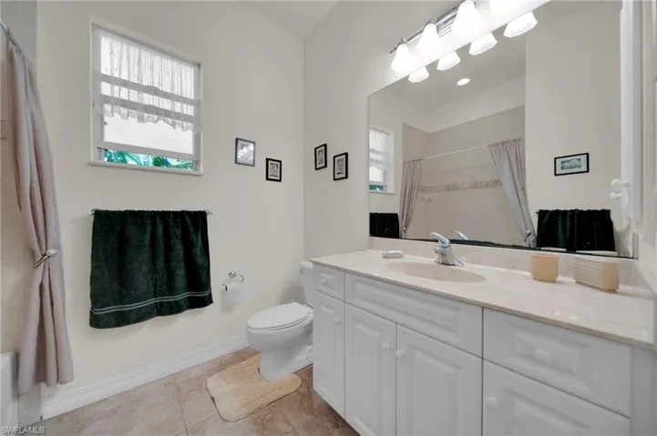 Full bath featuring baseboards, toilet, a shower with curtain, tile patterned floors, and vanity
