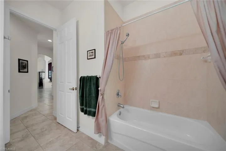 Full bath with tile patterned floors, baseboards, and shower / tub combo