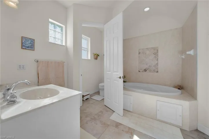 Full bath featuring a bath, toilet, baseboards, and a sink