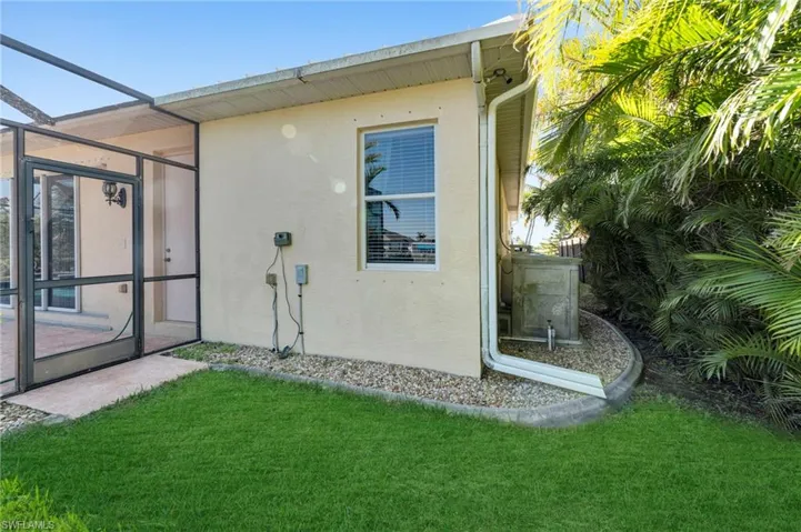 Rear view of property featuring a lanai, stucco siding, and a yard