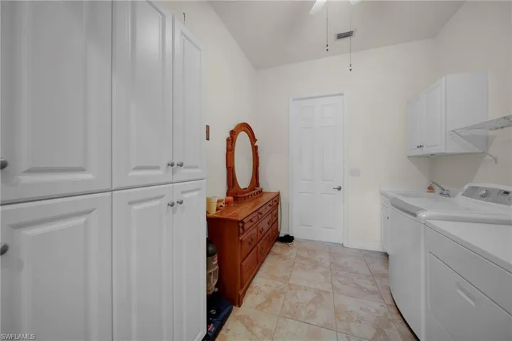 Washroom featuring visible vents, washing machine and dryer, cabinet space, light tile patterned flooring, and ceiling fan