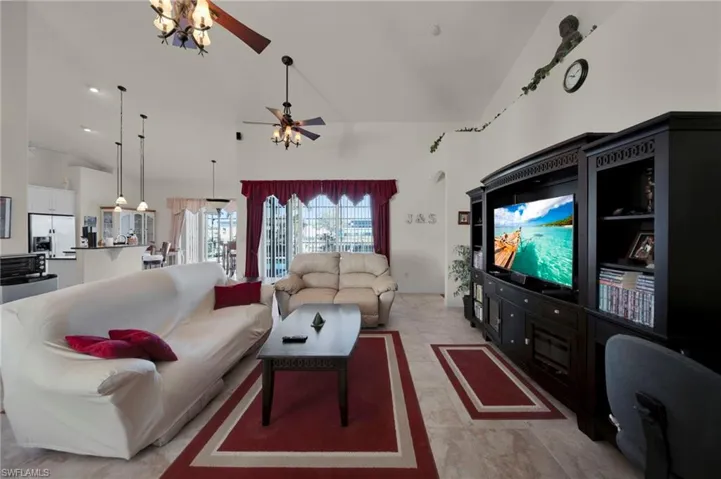 Living area with light tile patterned floors, high vaulted ceiling, and a ceiling fan