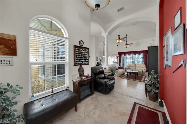 Living area featuring visible vents, ornate columns, arched walkways, high vaulted ceiling, and a ceiling fan