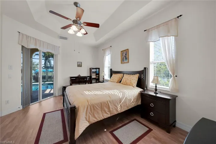 Bedroom featuring light wood-type flooring, a raised ceiling, baseboards, and access to exterior