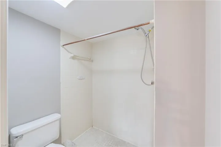 Bathroom featuring tiled shower and toilet