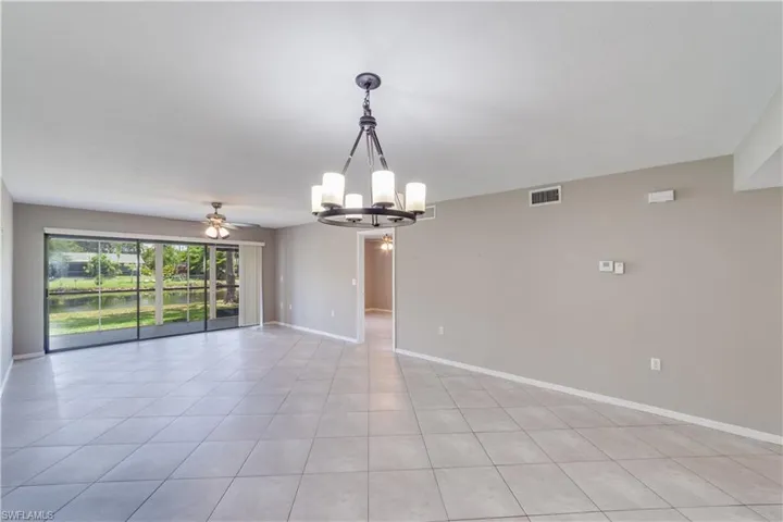 Unfurnished room with light tile flooring and ceiling fan with notable chandelier