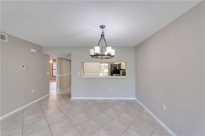 Unfurnished dining area with plenty of natural light, a chandelier, and light tile flooring