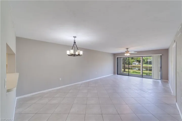 Tiled spare room featuring ceiling fan with notable chandelier