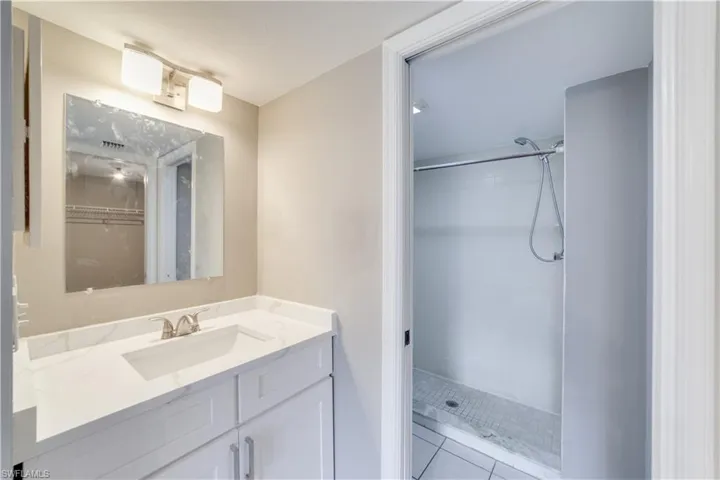 Bathroom featuring tiled shower, tile flooring, and vanity