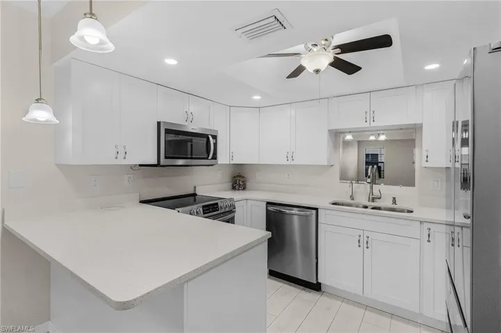 Kitchen with appliances with stainless steel finishes, a ceiling fan, light countertops, a peninsula, and recessed lighting