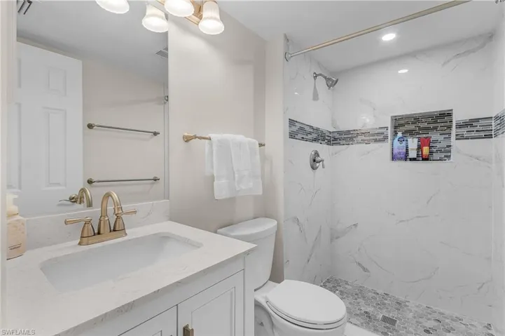 Bathroom featuring vanity and a marble finish shower