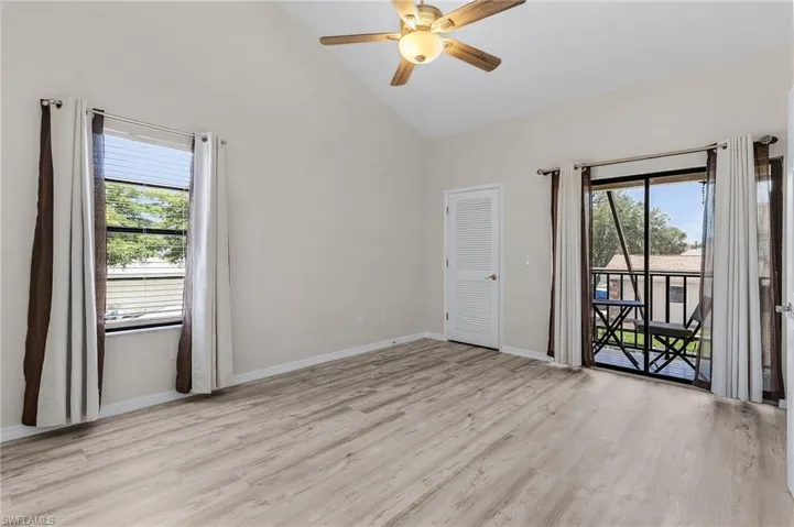 Spare room with light wood finished floors, healthy amount of natural light, high vaulted ceiling, and a ceiling fan