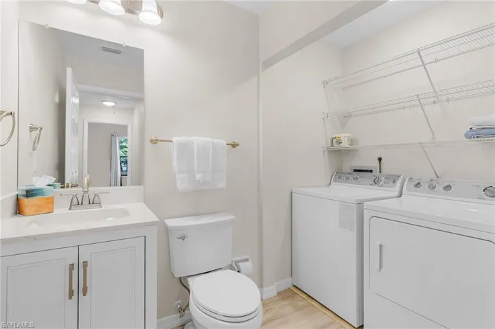 Bathroom featuring independent washer and dryer, vanity, and wood finished floors