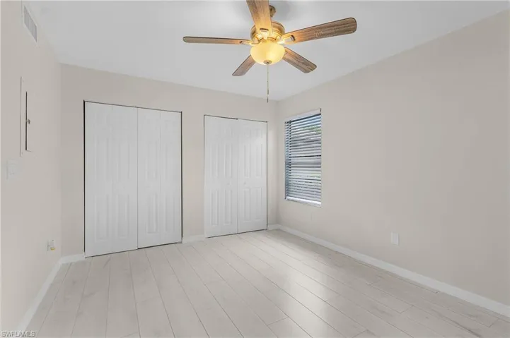 Unfurnished bedroom featuring two closets, light wood-style flooring, and ceiling fan